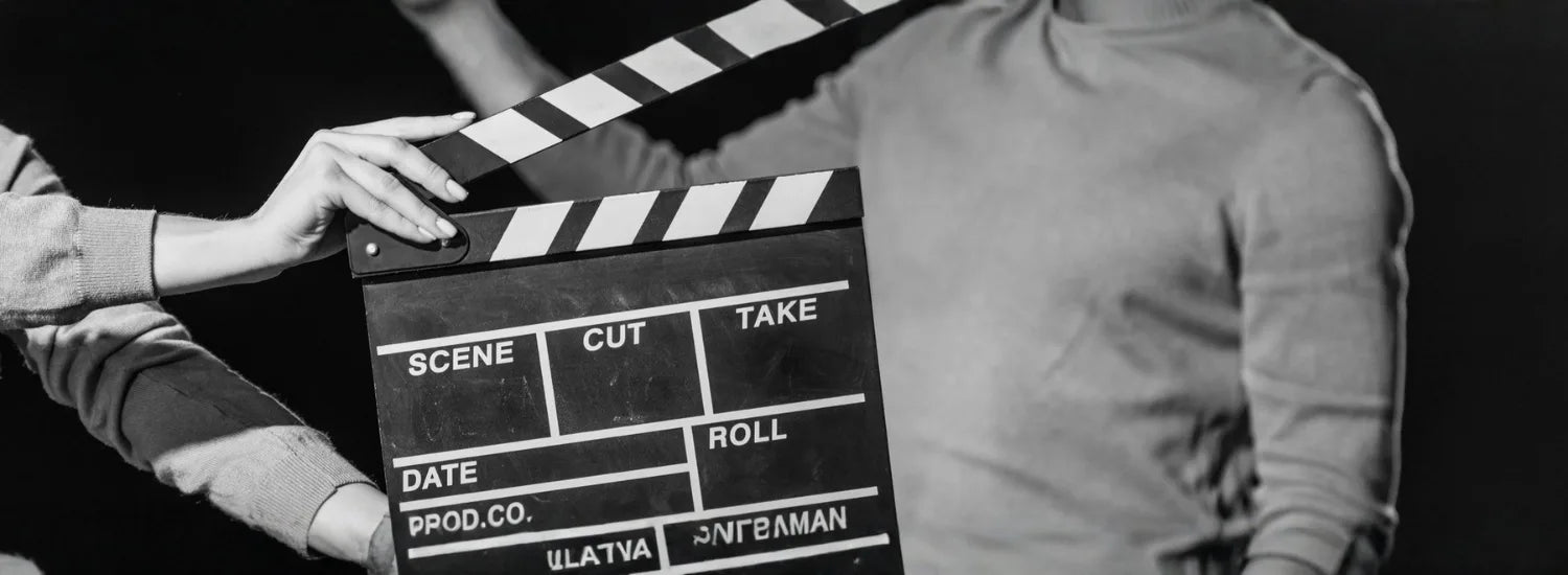 A black and white image of a movie clapper board for cutting and taking scenes, as well as several people in the background.