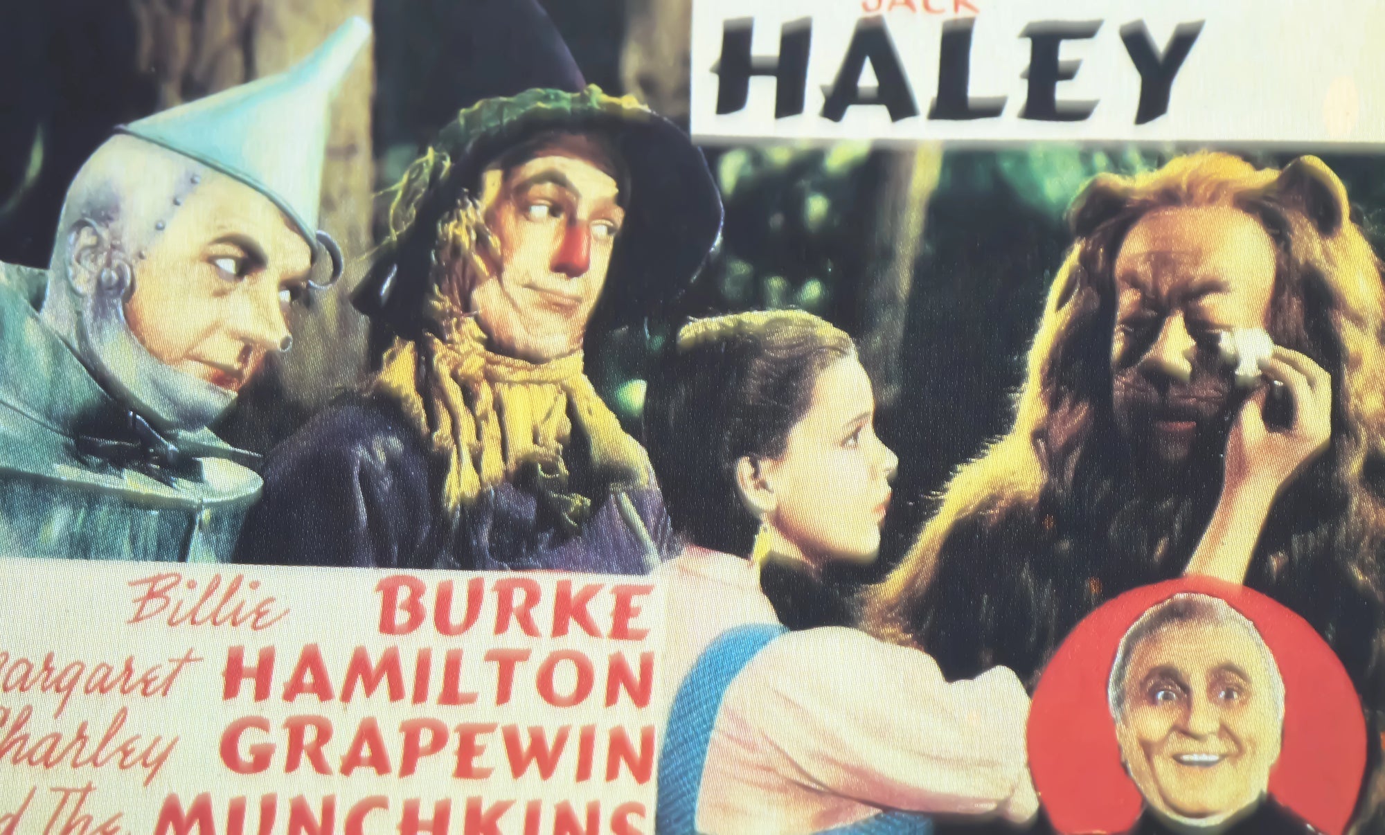 An old magazine clipping advertising The Wizard of Oz movie from 1939, showing the actors for Dorothy, the Tin Man, the Scarecrow, and the Lion checking one another’s makeup.